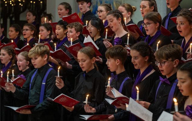 Young people singing by candlelight in a choir.