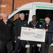 Four men standing in front of a bus holding a large cheque.