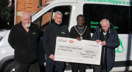 Four men standing in front of a bus holding a large cheque.