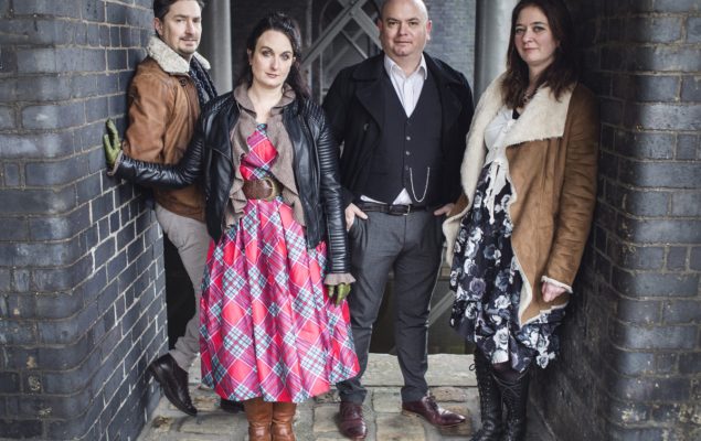 4 people, 2 males and 2 females stood in a line looking at the camera