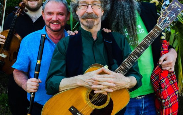 Man holding a guitar with band members behind him.